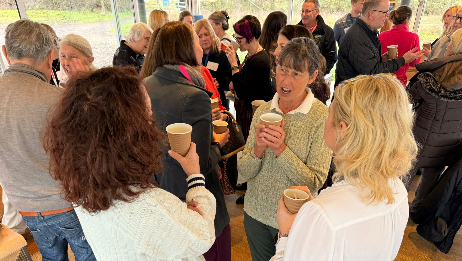 A crowd of SCN members chatting and networking with hot drinks