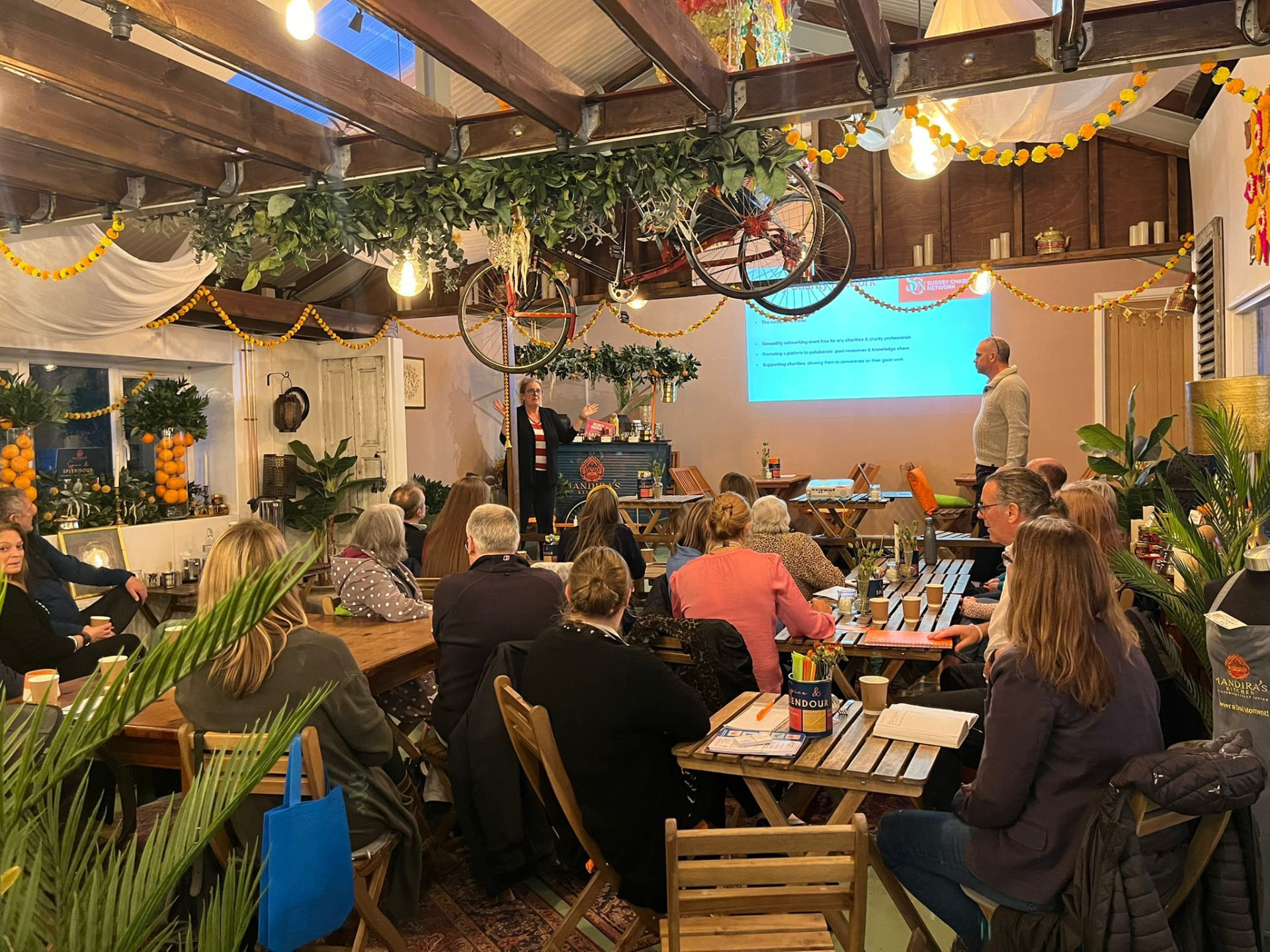 A guest speaker presenting to SCN members seated at wooden tables